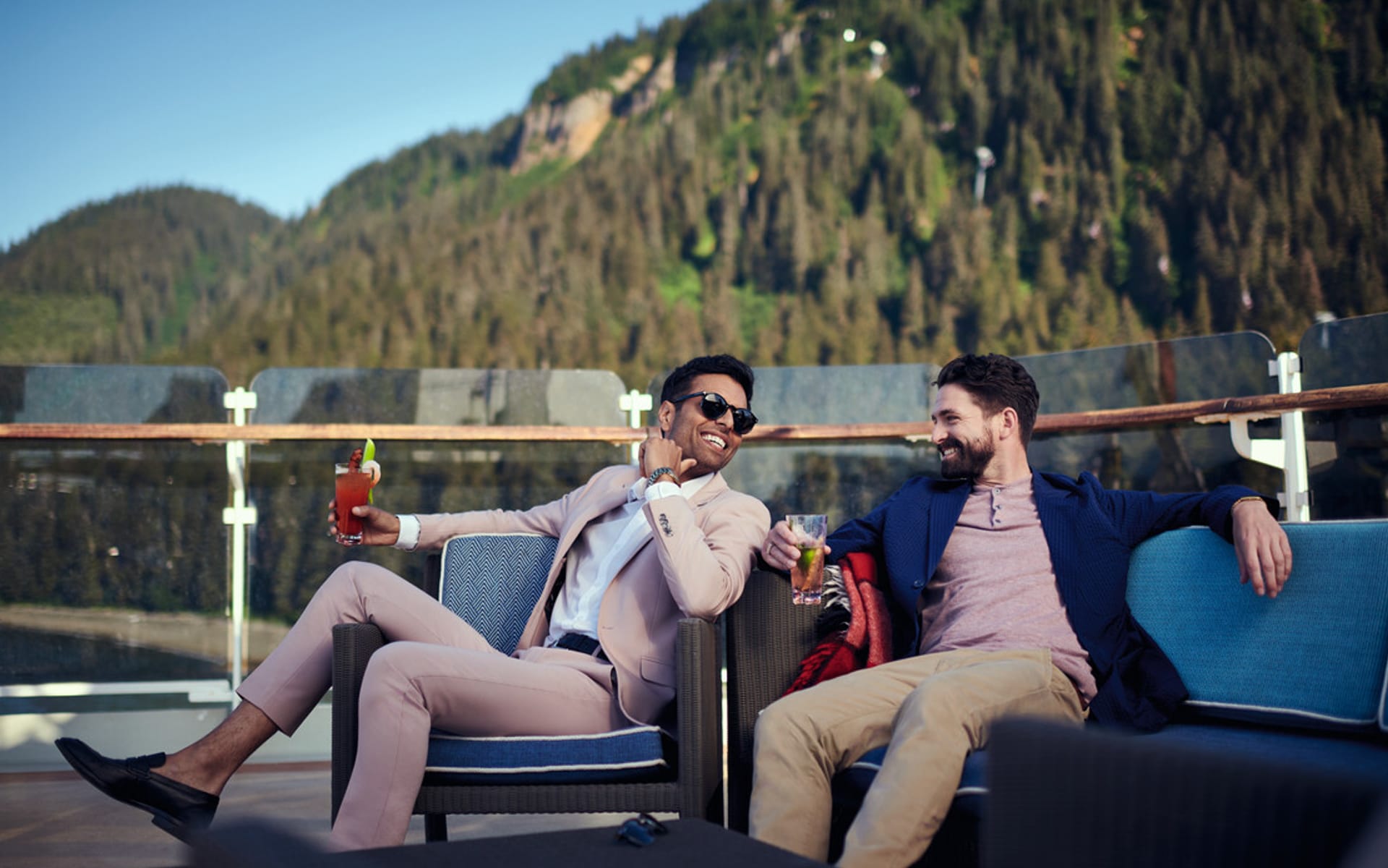 Two men enjoy a cocktail on the top deck of a cruise ship