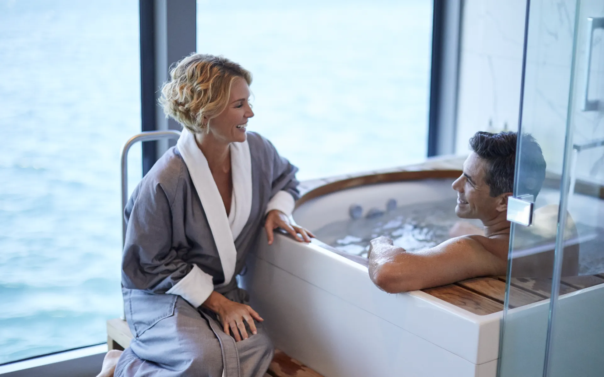 A man in a jacuzzi on a Celebrity Cruises ship with a woman sat besides him in a gown