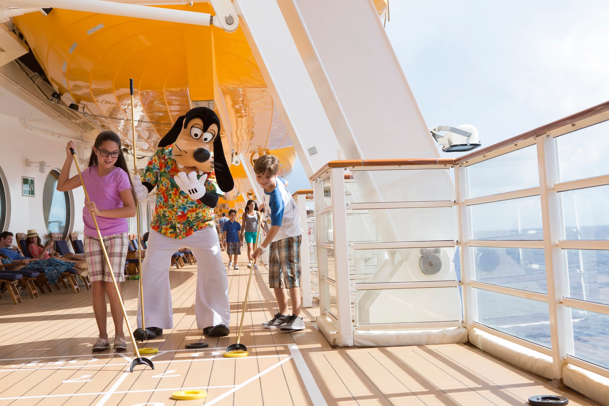 An image of Disney character Goofy on deck aboard a Disney Cruise Line ship with two children