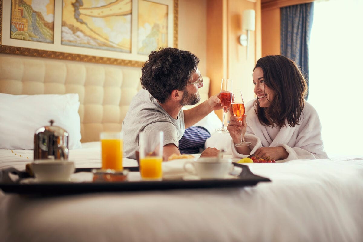 Two people sharing a glass of Champagne during breakfast in bed