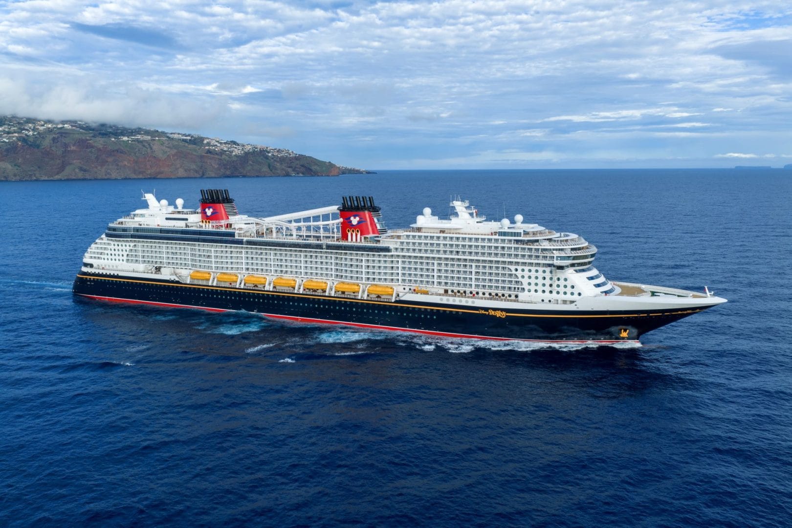 An image of a Disney Cruise Line cruise ship in semi-open, calm waters during the daytime